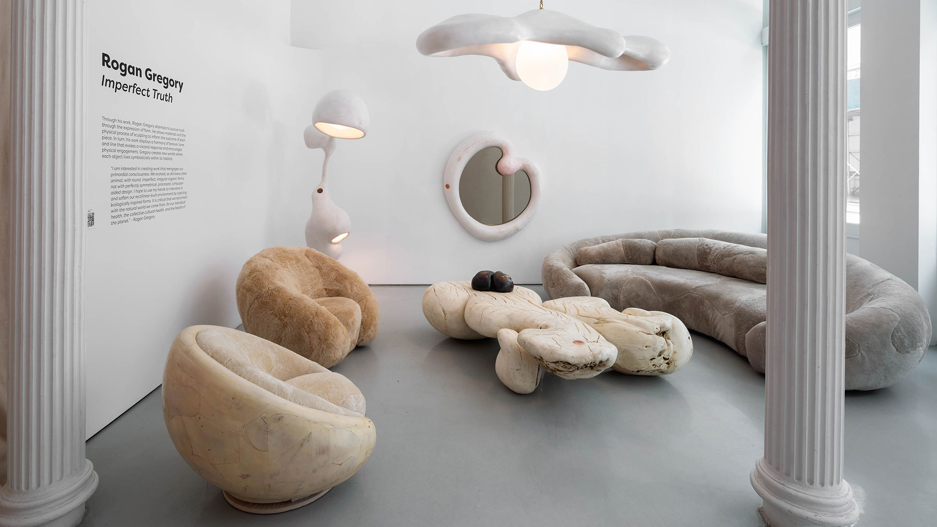 The setting includes a sofa, chairs, a coffee table, a sculpture and a mirror